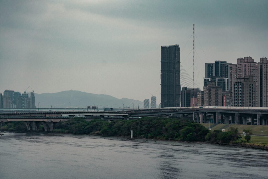 Skyline of Taipei City with its towering buildings and sprawling bridge over a river.