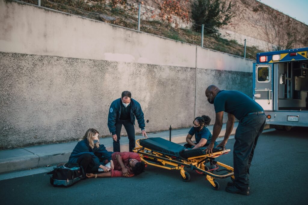 Emergency team helps an injured person on the street with a stretcher nearby.