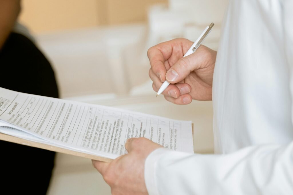 pexels-photo-7088483-7088483 A medical professional in a white coat examines a clipboard with patient documents.