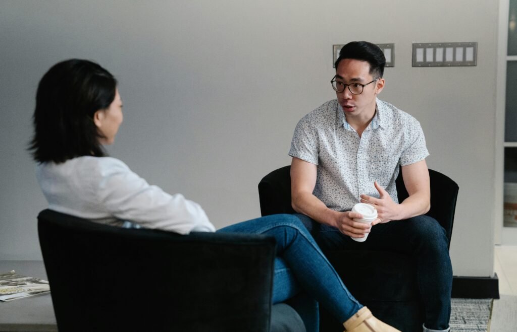 Two people having a casual conversation in an indoor setting, one holding a coffee cup, highlighting communication and relaxation.