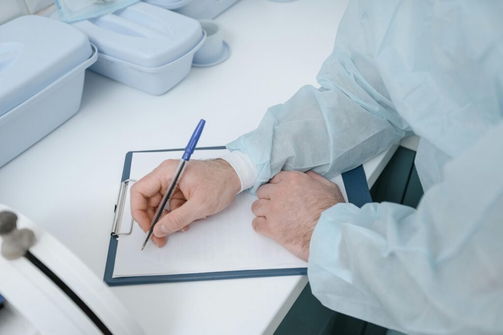 A medical professional wearing protective clothing writing on a clipboard.