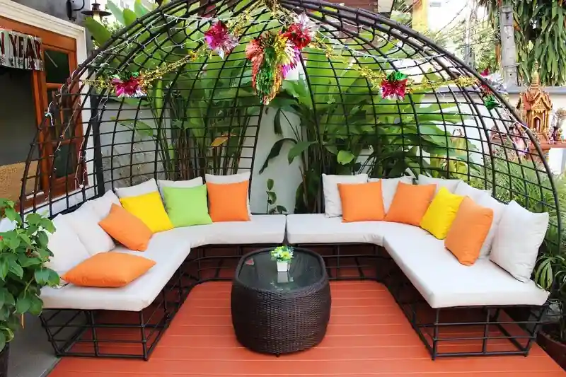 Conjunto jardín pérgola cojines naranjas ambiente tropical
