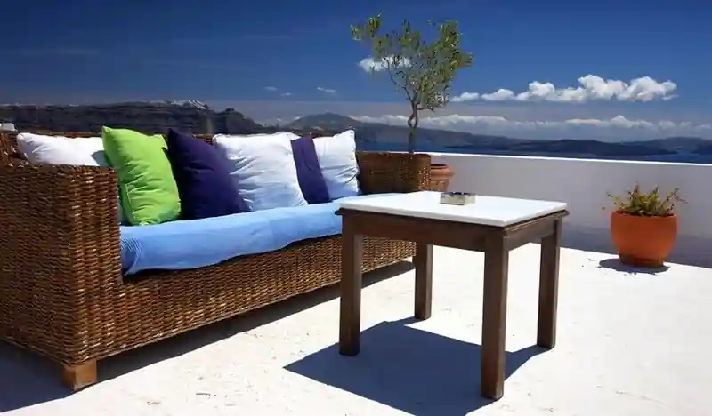 Sofá exterior cojines azules mesa madera vistas mar
